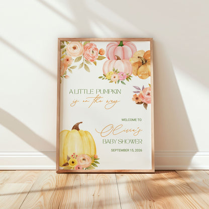 Framed baby shower welcome sign with pumpkins and flowers on a wooden floor.